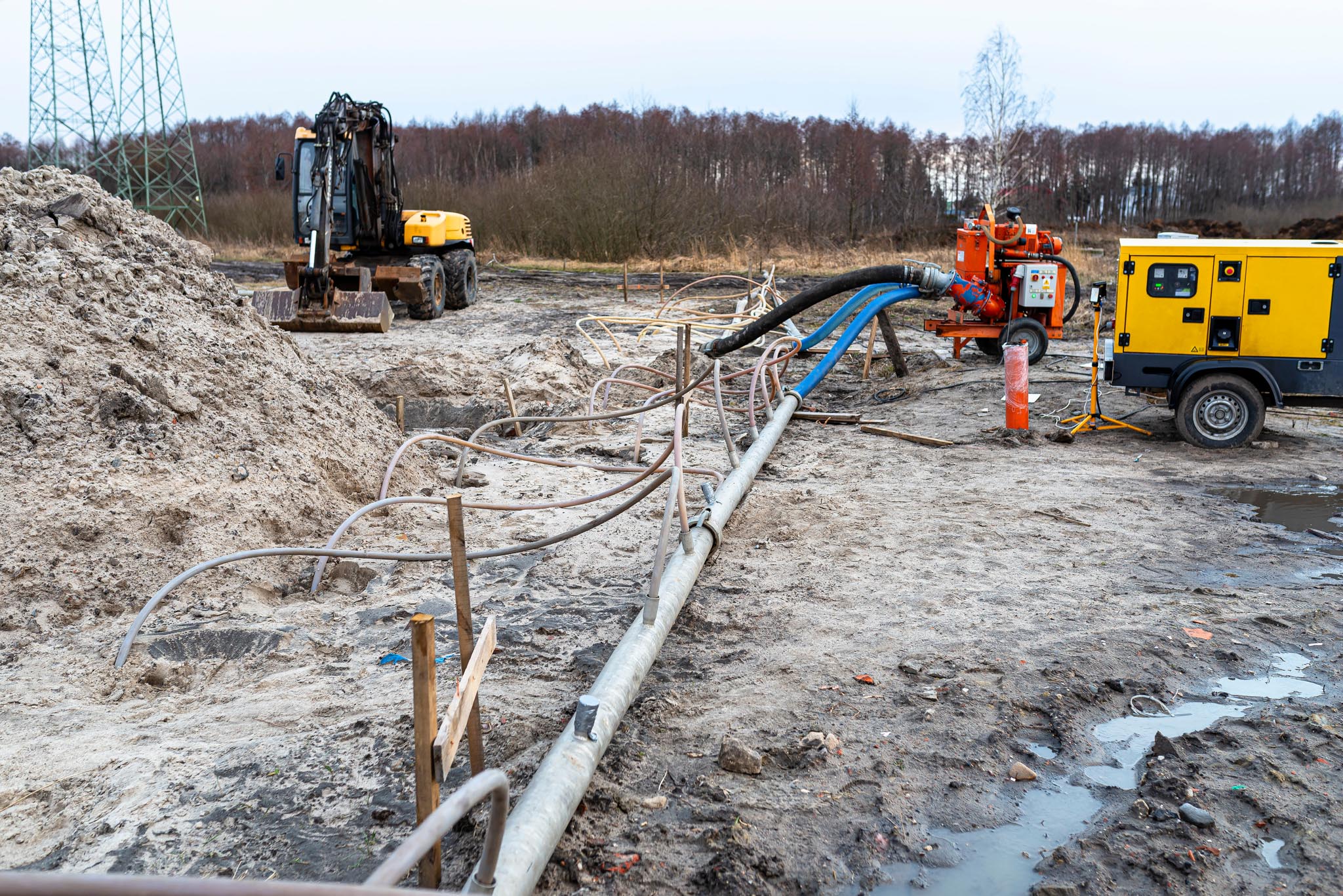 Wellpoint installation to get rid of high groundwater, visible metal and plastic pipes and a large water pump.